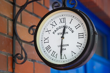 English brick house corner with retro clock with Paddington Station London text on it.