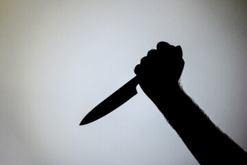 Projected silhouette on the wall of a male arm holding a knife