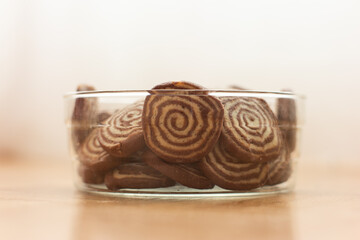 Home made round chocolate biscuits stacked in a glass pot isolated with shallow depth of field