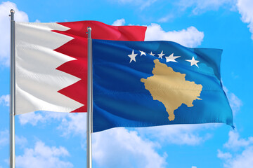 Kosovo and Bahrain national flag waving in the windy deep blue sky. Diplomacy and international relations concept.
