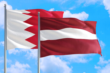 Latvia and Bahrain national flag waving in the windy deep blue sky. Diplomacy and international relations concept.