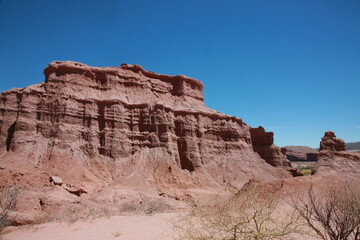 Fototapeta premium The red rocks of sandstone stand on desert area against blue sky background.