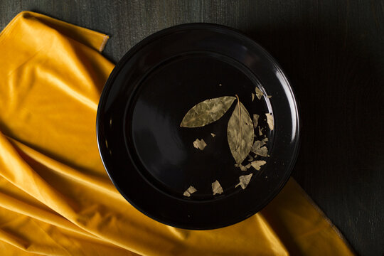 High Angle Shot Of Dried Leaves In A Black Plate On The Table