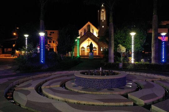 Puyo, Ecuador, 19-6-2020: night view a fontain in a public park with a church in the background