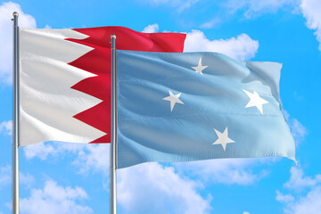 Micronesia and Bahrain national flag waving in the windy deep blue sky. Diplomacy and international relations concept.