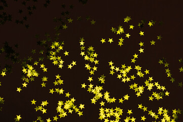 Golden stars on black background. Flat lay, top view. Selective focus.