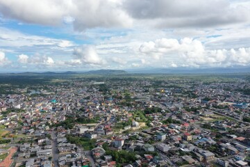 Aerial view over a large city with a beautiful cloudscape and in green covered hills in the background