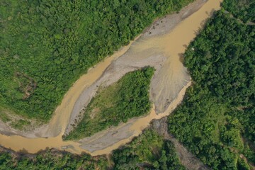 Aerial view or top view showing a large brown river in a tropical rainforest