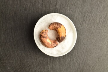 Several roasted cashews, close-up, on a slate board.