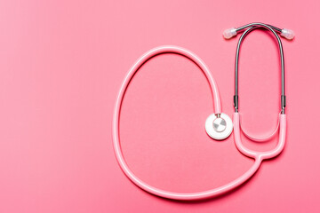 Fototapeta premium Top view of stethoscope on pink background, concept of breast cancer awareness