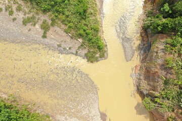 Aerial view or top view of two tropical rivers merging together in one large brown colored river in...