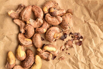 Fragrant fried salted cashews on brown paper, close-up.