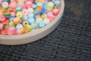 Colored decorative beads on a glass saucer.