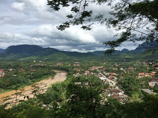 Fototapeta na wymiar Tropical city in Laos, South East Asia that is divided by a large brown colored river seen from a distance
