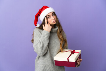 Girl with christmas hat holding a present isolated on white background thinking an idea