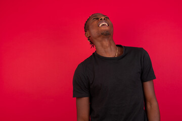 Young African American handsome man standing against red background laughing out loud after hearing a good joke 