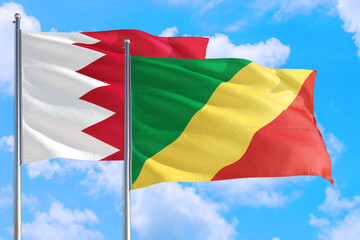 Republic Of The Congo and Bahrain national flag waving in the windy deep blue sky. Diplomacy and international relations concept.