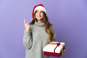 Girl with christmas hat holding a present isolated on white background pointing up a great idea