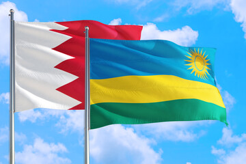 Rwanda and Bahrain national flag waving in the windy deep blue sky. Diplomacy and international relations concept.