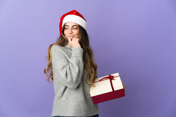 Girl with christmas hat holding a present isolated on white background and looking up