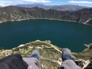 Feet sticking out at the crater of lake Quilotoa, a typical tourist selfie