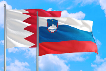 Slovenia and Bahrain national flag waving in the windy deep blue sky. Diplomacy and international relations concept.