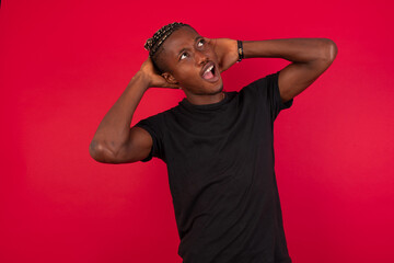 Young African American handsome man standing against red background relaxing and stretching, arms and hands behind head and neck smiling happy