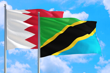 Tanzania and Bahrain national flag waving in the windy deep blue sky. Diplomacy and international relations concept.