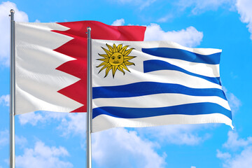 Uruguay and Bahrain national flag waving in the windy deep blue sky. Diplomacy and international relations concept.