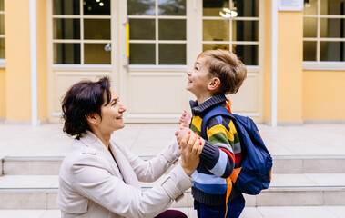 Parent take child to school. Pupil of primary school go study with backpack outdoors. Father and son go hand in hand. Beginning of lessons. Back to school. First day of fall. Elementary student.