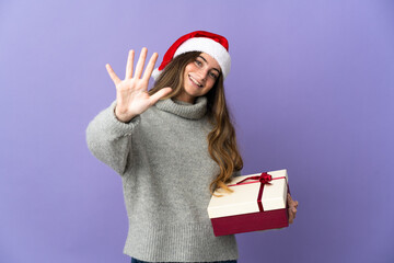 Girl with christmas hat holding a present isolated on white background counting five with fingers