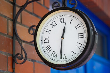 Street clock on the brick wall of an English house