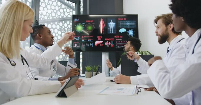 Good-looking positive successful experienced mixed race doctors advising about risks heart deseases during briefing in conference room,front view