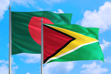 Guyana and Bangladesh national flag waving in the windy deep blue sky. Diplomacy and international relations concept.