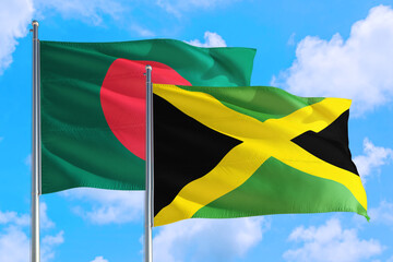 Jamaica and Bangladesh national flag waving in the windy deep blue sky. Diplomacy and international relations concept.