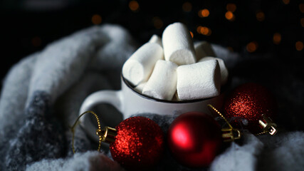 Mug of hot chocolate with marshmallow on a dark background, winter Christmas hot drink with red christmas balls and bokeh lights