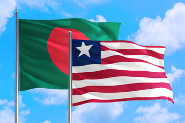 Liberia and Bangladesh national flag waving in the windy deep blue sky. Diplomacy and international relations concept.