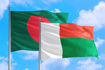 Madagascar and Bangladesh national flag waving in the windy deep blue sky. Diplomacy and international relations concept.