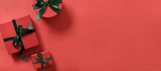 Christmas red gifts and decorative green rope ribbon on red surface. Top view. Xmas. Space for text.