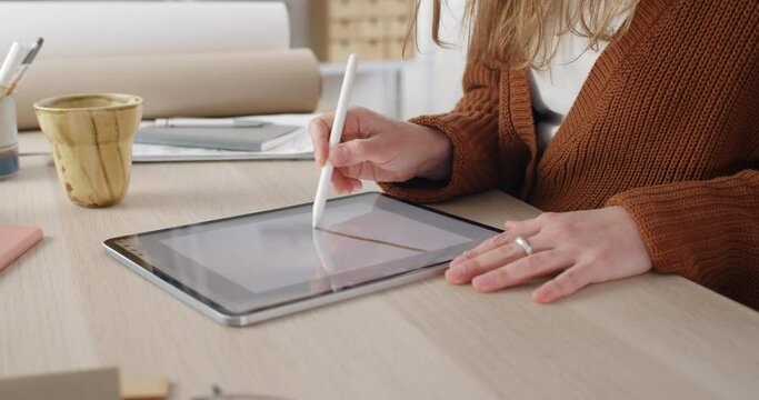 Crop view of female web designer choosing brush size while drawing digital picture. Focus on woman hands using stylus while creating illustration on tablet.Concept of modern art