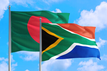 South Africa and Bangladesh national flag waving in the windy deep blue sky. Diplomacy and international relations concept.