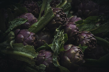 A pile of artichokes on a market stall. Close up photo with shallow focus.