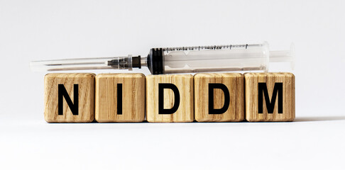 Text NIDDM made from wooden cubes. White background