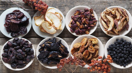 Bowls with various dried fruits on a wooden ancient background. Home preparation of dried fruits.