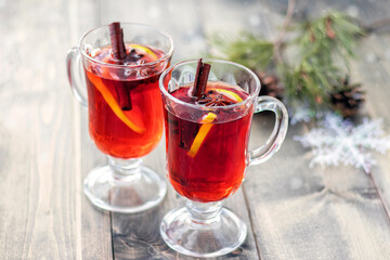 Mulled wine for Christmas. Two cups with mulled wine on wooden table with blur snow and branch of Christmas tree. Concept Christmas or New Year. Xmas.