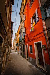 Fototapeta na wymiar romantic and characteristic Italian colorful street with multi colored houses in Chioggia near Venice, with sunset light