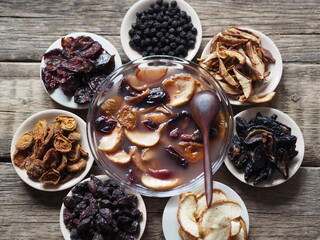 Kissel with dried fruits surrounded by dried fruits on plates on a wooden background. Healthy...