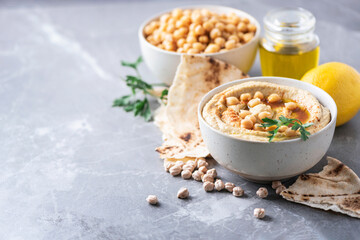 Chickpeas hummus, olive oil, raw chickpeas, smoked paprika, pita on grey background. Middle eastern, jewish cuisine or arabic dishes. Macro view. Copy space. Snacks set. Vegan, vegetarian food concept