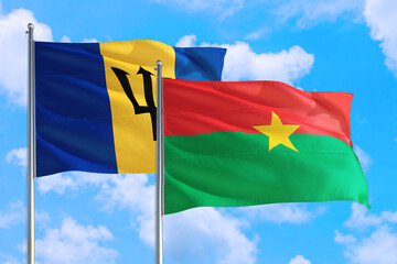 Burkina Faso and Barbados national flag waving in the windy deep blue sky. Diplomacy and international relations concept.