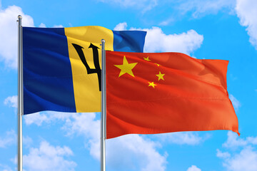 China and Barbados national flag waving in the windy deep blue sky. Diplomacy and international relations concept.
